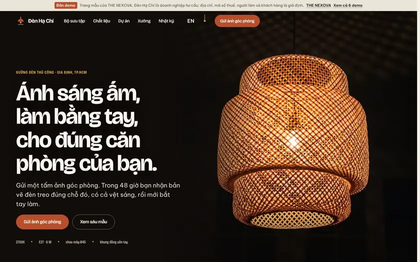 Trang chủ website mẫu Đèn Hạ Chí trên nền tối: tiêu đề "Ánh sáng ấm, làm bằng tay, cho đúng căn phòng của bạn." cạnh ảnh chụp một chiếc đèn mây đan đang sáng, nút gửi ảnh góc phòng.